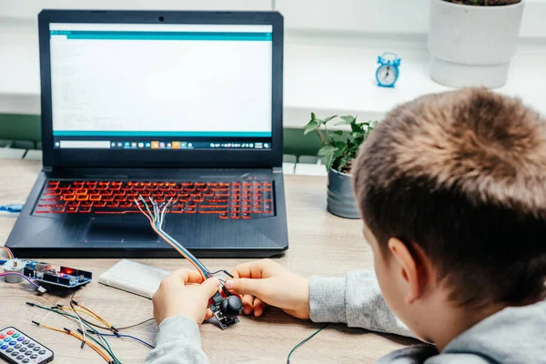 Um menino conectando cabos aos chips do sensor ao aprender a codificação e a robótica do arduino — Fotografia de Stock