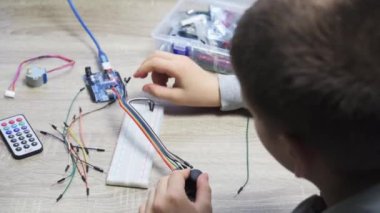 Arduino kodlama ve robotik öğrenirken algılayıcı çiplerine kablo takan bir çocuk