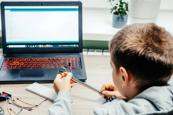 Um menino conectando cabos aos chips do sensor ao aprender a codificação e a robótica do arduino — Fotografia de Stock