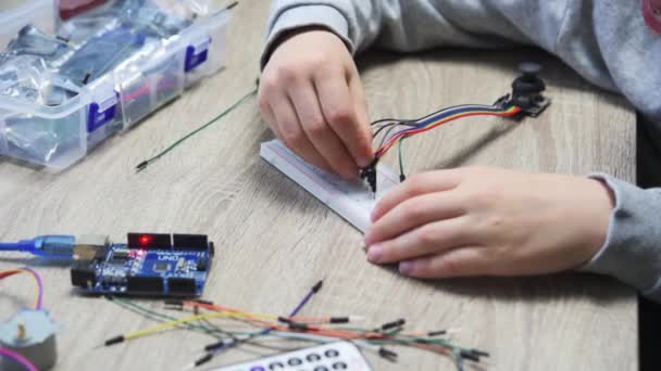 Ein Kind steckt Kabel an Sensorchips, während es Arduino-Codierung und Robotik lernt — Stockvideo