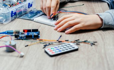 Arduino kodlama ve robotik öğrenirken algılayıcı çiplerine kablo takan bir çocuk