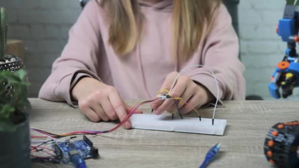 Uma menina adolescente loira conectando cabos a chips de sensor enquanto aprende a codificação e robótica de arduino — Vídeo de Stock