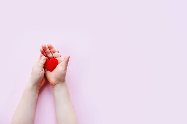 Детская рука, держащая красное сердце на розовом фоне с пространством для копирования, фон Дня святого Валентина