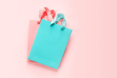 Pembe zemin üzerinde mercan ve turkuaz alışveriş torbaları. Ürün yerleştirme için fotokopi alanı ve maket.
