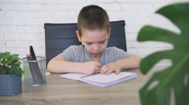 Masada defterine resim çizen sevimli küçük çocuk.