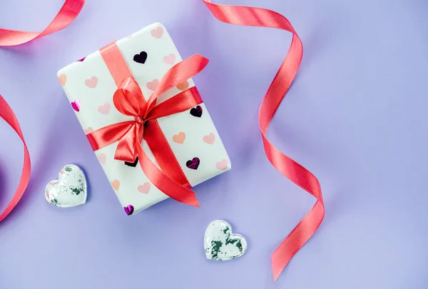 Caja de regalo de San Valentín con corazones y cinta roja sobre fondo violeta púrpura —  Fotos de Stock