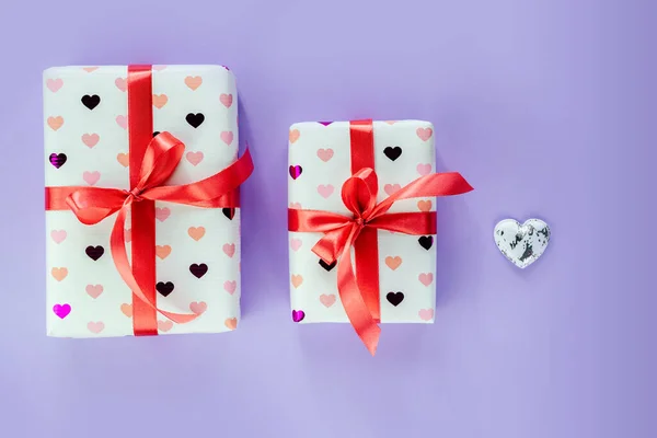 Подарочные коробки, завернутые в бумагу сердца с красной лентой бант на розовом фоне — стоковое фото