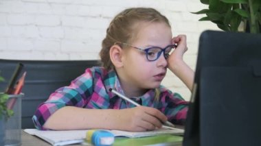 Gözlüklü ilkokul çocuğu, okul çıkışları kapatılırken internette ders yazarken çocuklara uzaktan eğitim veriyor.