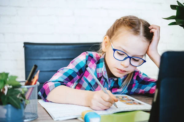 Klein meisje in bril studeren online thuis, een basisschool meisje met computer met zoom video chat met leraar — Stockfoto