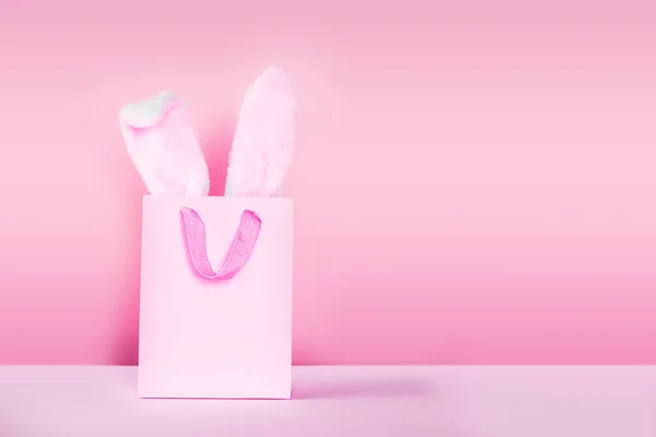 Påsk shopping sammansättning med kanin öron ur shoppingväska på rosa bakgrund — Stockfoto