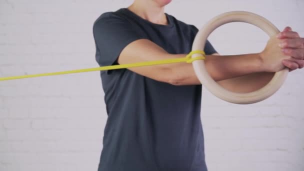 Una mujer realiza ejercicios con banda de resistencia y anillo de madera — Vídeos de Stock