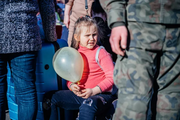 Medyka, Polônia - 24 de março de 2022: Uma menina com um balão entre a multidão de pessoas de uniforme militar na fronteira ucraniano-polonesa que atravessa Medyka. Pessoas que fogem da guerra na Ucrânia Imagens De Bancos De Imagens Sem Royalties