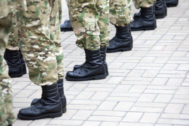 Siyah asker çizmeleri giymiş bacaklar. Askere alınma..