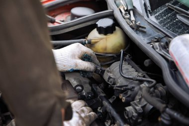 Bir insan ustası bir araba motorunu eldivenle tamir eder..