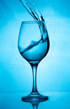 Bir bardak şarap, mavi arka planda bir tutam şarap mavisi su. Mavi arka planda şarap damlatan bir bardak. Barda, kafede, restoranda, gece kulübünde veya diskoda cam var.