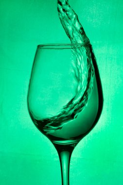 Bir bardak şarap, yeşil arka planda biraz şarap yeşili su. Yeşil arka planda şarap damlatan bir bardak. Barda, kafede, restoranda, gece kulübünde veya diskoda cam var.