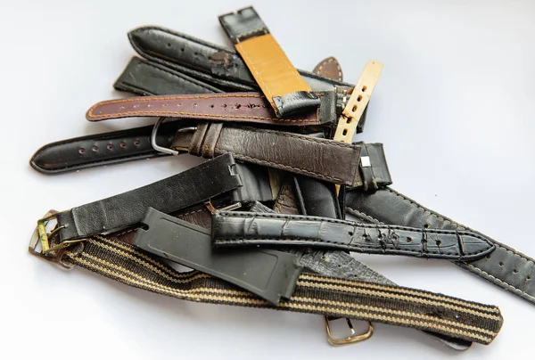 Old worn leather watch bracelets with a clasp in a pile.