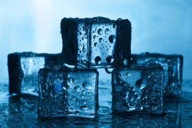 Mavi arka planda pürüzsüz buz küpleri. Küçük damlalı soğuk buz. Yavaşça eriyen buz