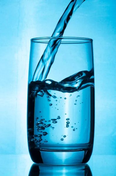 Склянку Чистої Води Наливають Струмінь Води Стакан Води Синьому Фоні — стокове фото