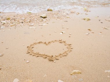 Sahilde el yazısı kalp şeklinde, deniz kenarında kumsalda.