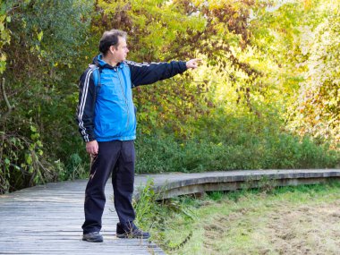 Orta yaşlı turist, güz doğasında yürüyüş, tahta yol, güneşli bir gün.