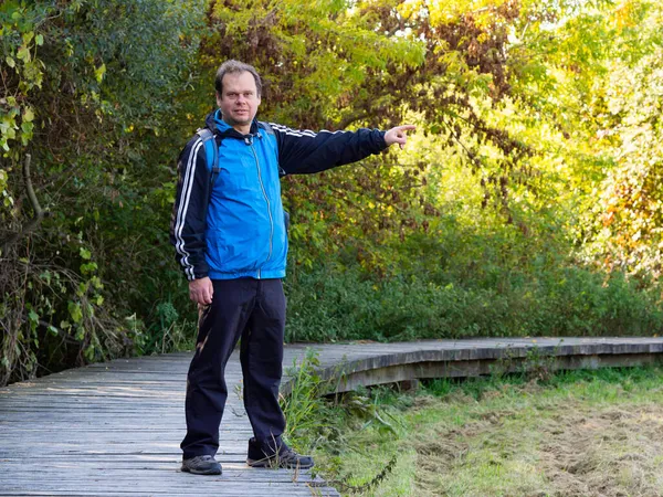 Orta yaşlı turistleri işaret eden adam, sonbahar yürüyüşünün tadını çıkarıyor.