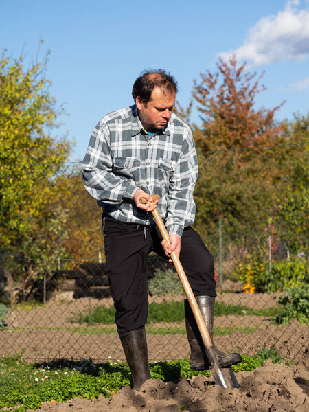 Gardening, man digging the garden bed with spade on sunny day