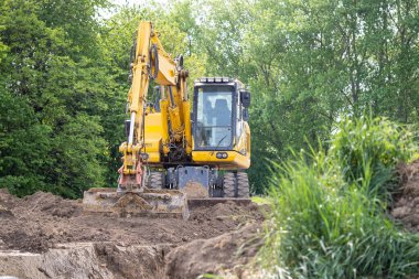 Yellow excavator in construction site digging soil