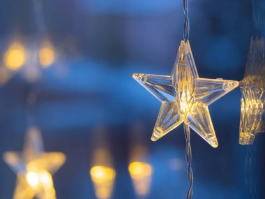 Detail of shining LED chain with stars, Christmas decoration hanging on window