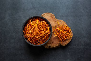 Kurumuş Cordyceps askeri mantarı koyu gri arka planda kasede. Cordyceps çiçeği