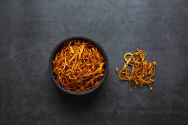 Kurumuş Cordyceps askeri mantarı koyu gri arka planda kasede. Cordyceps çiçeği
