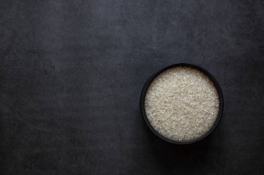 Pirinç kasede ve kaşık koyu gri arka planda.