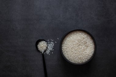 Pirinç kasede ve kaşık koyu gri arka planda.