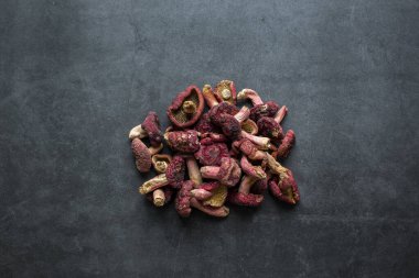 Parlak kırmızı mantar, koyu gri arka planda kurutulmuş kırmızı mantarda iyi bir besin kaynağıdır..