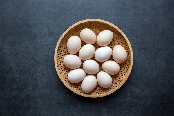 濃い灰色の背景に竹籠の中の新鮮な鶏の卵 — ストック写真