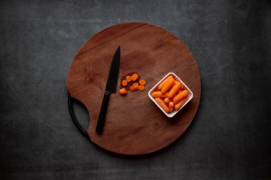 Koyu gri arka planda tahta üzerinde havuç dilimleri.