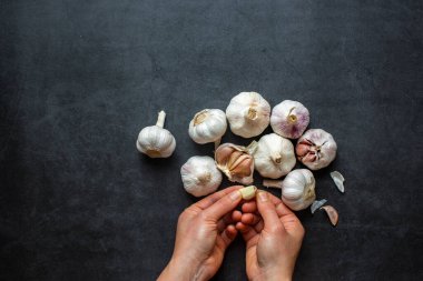 Sarımsak ve sarımsak ve koyu gri arka planda dilimlenmiş sarımsak..