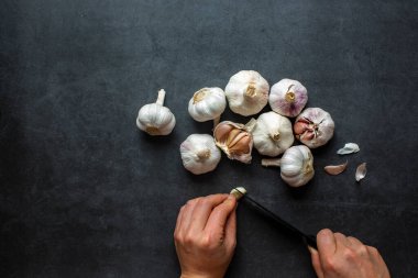 Sarımsak ve sarımsak ve koyu gri arka planda dilimlenmiş sarımsak..