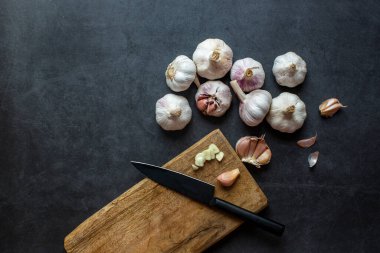 Sarımsak ve sarımsak ve koyu gri arka planda dilimlenmiş sarımsak..