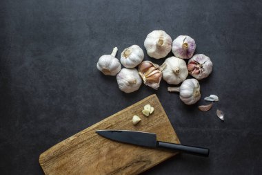 Sarımsak ve sarımsak ve koyu gri arka planda dilimlenmiş sarımsak..