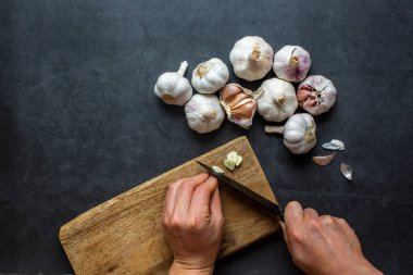 Sarımsak ve sarımsak ve koyu gri arka planda dilimlenmiş sarımsak..
