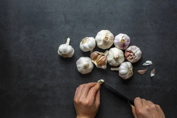 Sarımsak ve sarımsak ve koyu gri arka planda dilimlenmiş sarımsak..