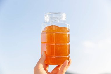 Bir kadının eli bal kavanozunu tutuyor.