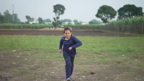 Hindistan 'ın tarım alanında koşan Hintli bir çocuğun yavaş çekimi. Arka planda şeker kamışı kırıntısı var. Hintli çocuk beden eğitimi için koşuyor.. — Stok video