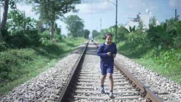 インドのヒマラヤ山脈の鉄道線路を走っているインドの子供、背景の緑。体力訓練. — ストック動画