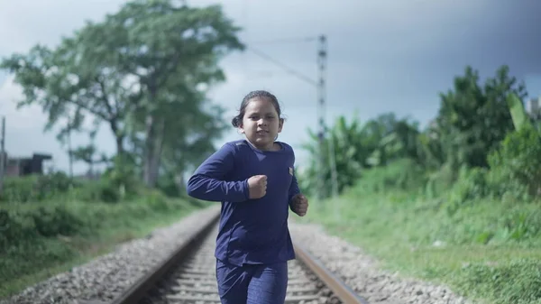 Indian Kid biegnie po torze kolejowym w Himalajach w Indiach, zieleń w tle. Trening sprawności fizycznej. — Zdjęcie stockowe