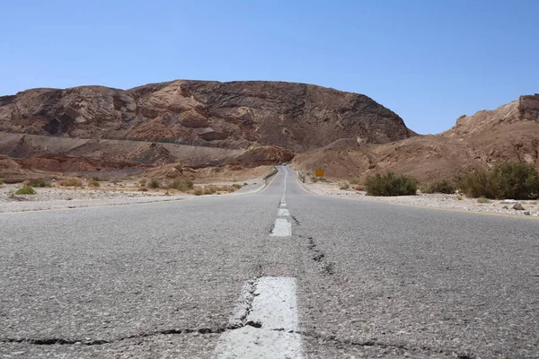 Asphalt gray road for car under blue sky in the desert way wasteland during journey to Eilat Breaks in the road