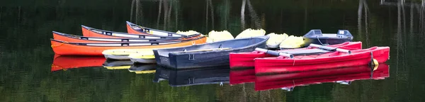 Vermelho azul e amarelo canoas de caiaque em fileira ancorado no lago — Fotografia de Stock