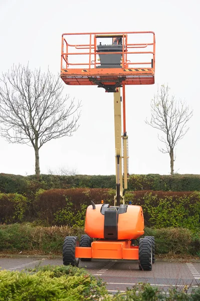 Équipement de plate-forme d'accès alimenté haut dans le ciel en orange pour la haute sécurité de la plate-forme de travail sur le chantier — Photo