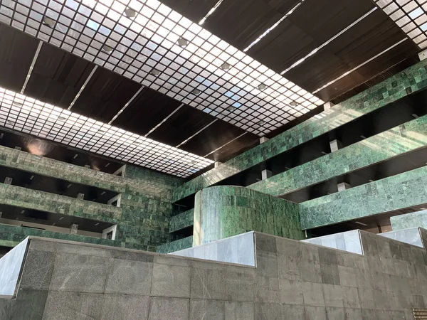 Low angle view of minimalist interior inside a lobbyhall of an office building. Interior with green marblewalls and glass ceiling.
